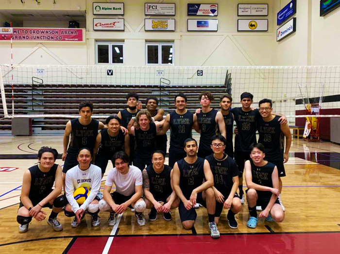 Picture of the men's volleyball team in front of a net in a gymnasium