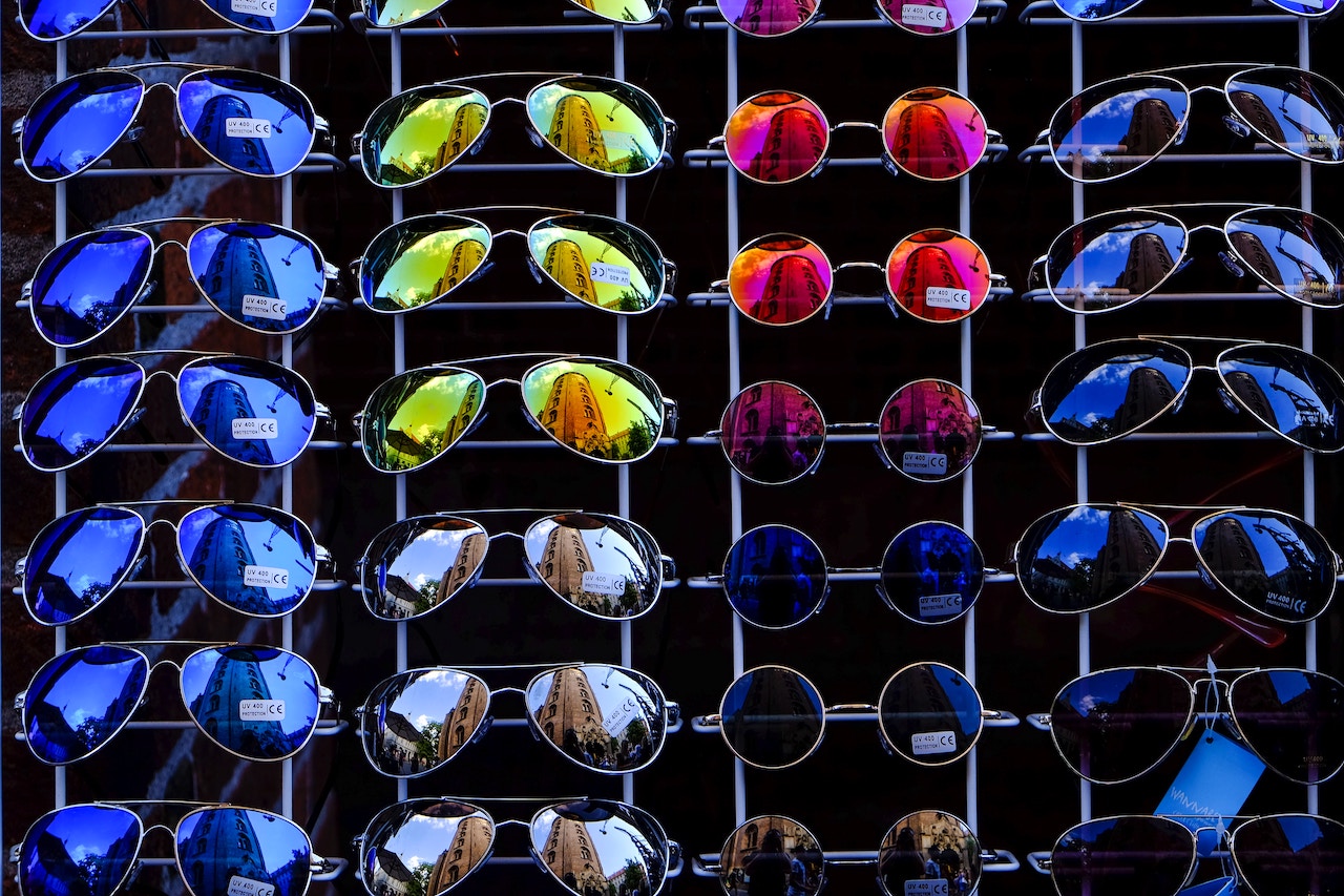 Assorted sizes and colors of sunglasses hanging on a wall