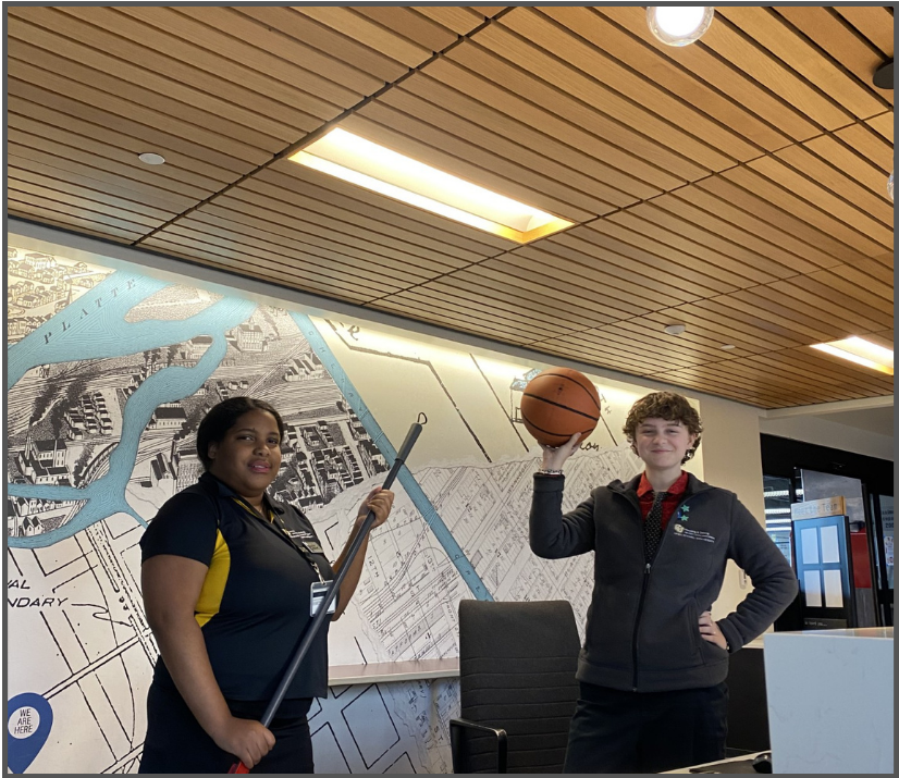 Two Desk Assistants holding a basketball and a broom