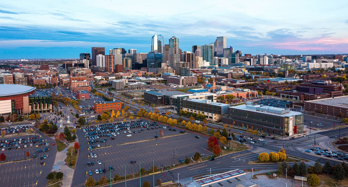 Aerial view of the Denver skyline with the Ball Arena parking lot area in the foreground.