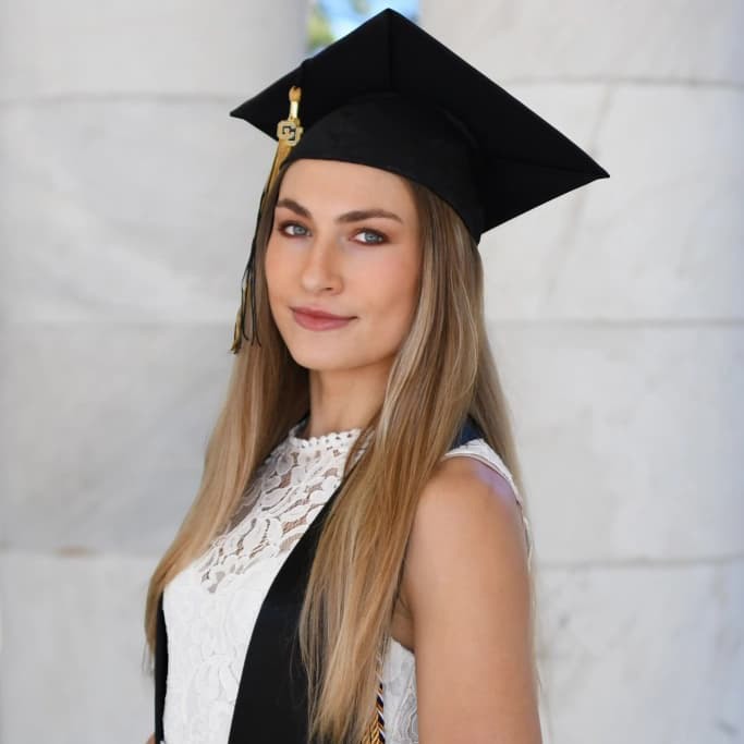 Lily Williams in a grad cap and long, blonde hair smiling at the camera.