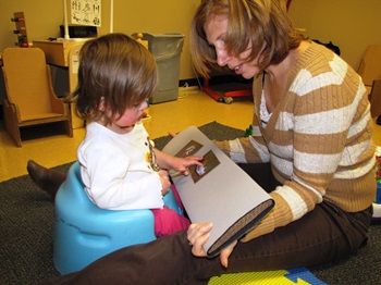 a toddler sits in an adapted seat interacts with a velcro storybook
