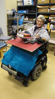 an older woman smiles while driving her switch controlled wheelchair