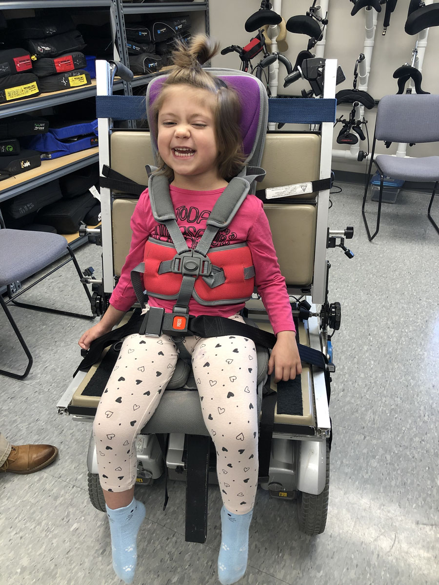 a young girl sits in a power wheelchair seating simulator