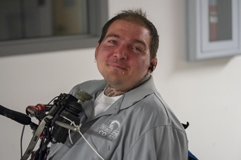 a gentleman poses with his chin control wheel chair  joystick