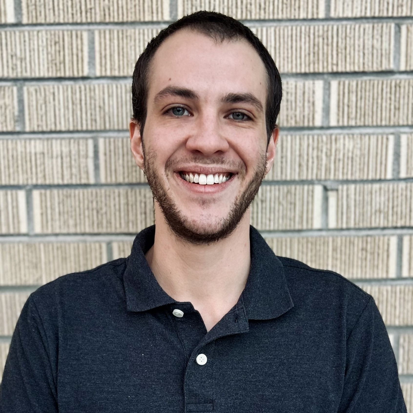 Elijah smiling outdoors in business casual attire