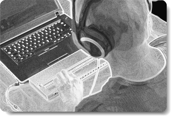 Young man using braille keyboard on laptop with headphones.