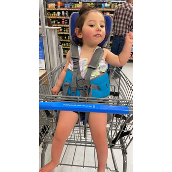 Happy child sitting upright independently in a shopping cart using her GoTo Postural Seat.