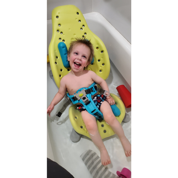Smiling child enjoying bath time, sitting independently, while using Splashy Seat.