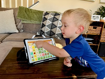 young boy pointing to word on AAC device