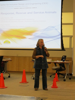Julia Beems presenting on Emergency preparedness for persons with disabilities. Emergency cones are seen on the floor nearby