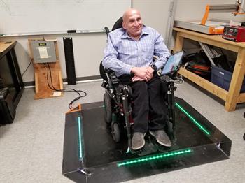 a gentleman in a wheelchair charging on a wireless charging pad