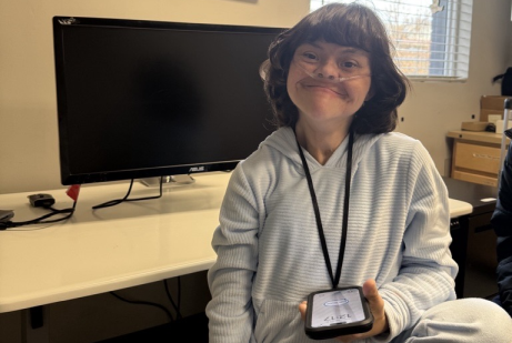 Smiling young woman holds her mobile app based AAC device.